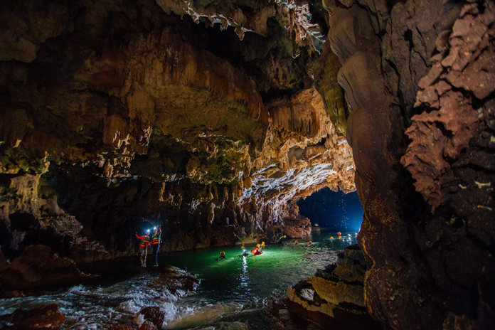 Swim along the underground river in Kim Cave.